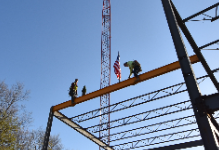 Two workers secure a construction beam